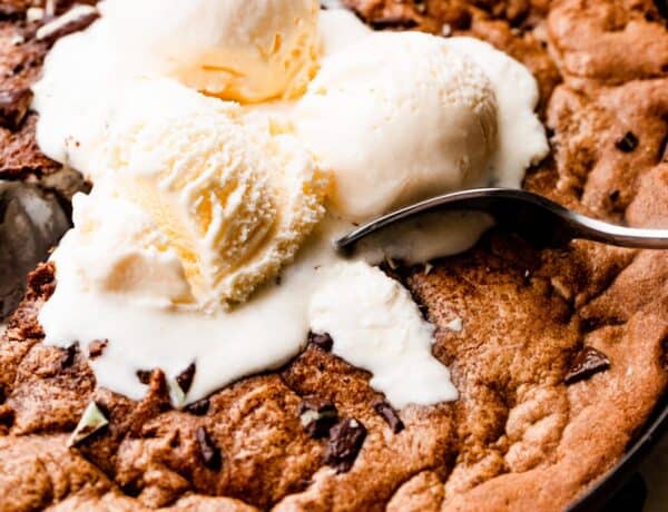close up overhead shot of three vanilla ice cream scoops set on top of a large skillet cookie.