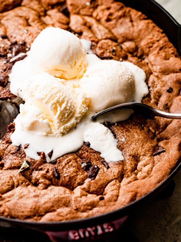 close up overhead shot of three vanilla ice cream scoops set on top of a large skillet cookie.