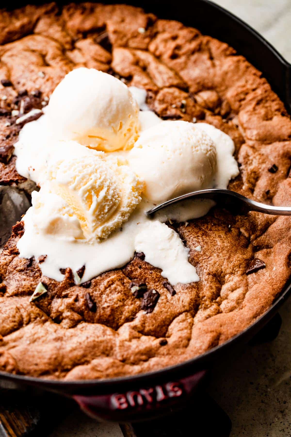 close up overhead shot of three vanilla ice cream scoops set on top of a large skillet cookie.