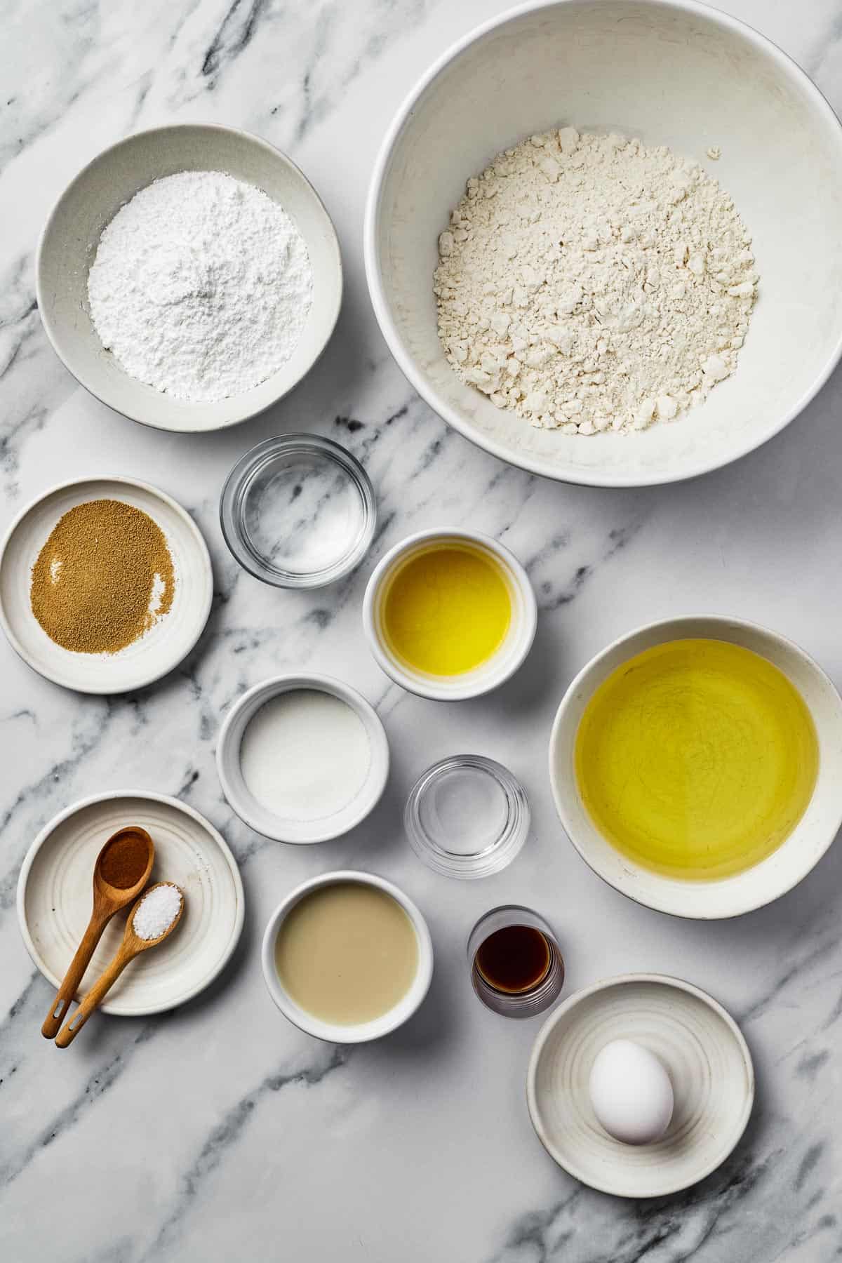 From top left: Powdered sugar, flour, yeast, water, melted butter, canola oil, sugar, vinegar, cinnamon, salt, brown sugar, vanilla, one egg.