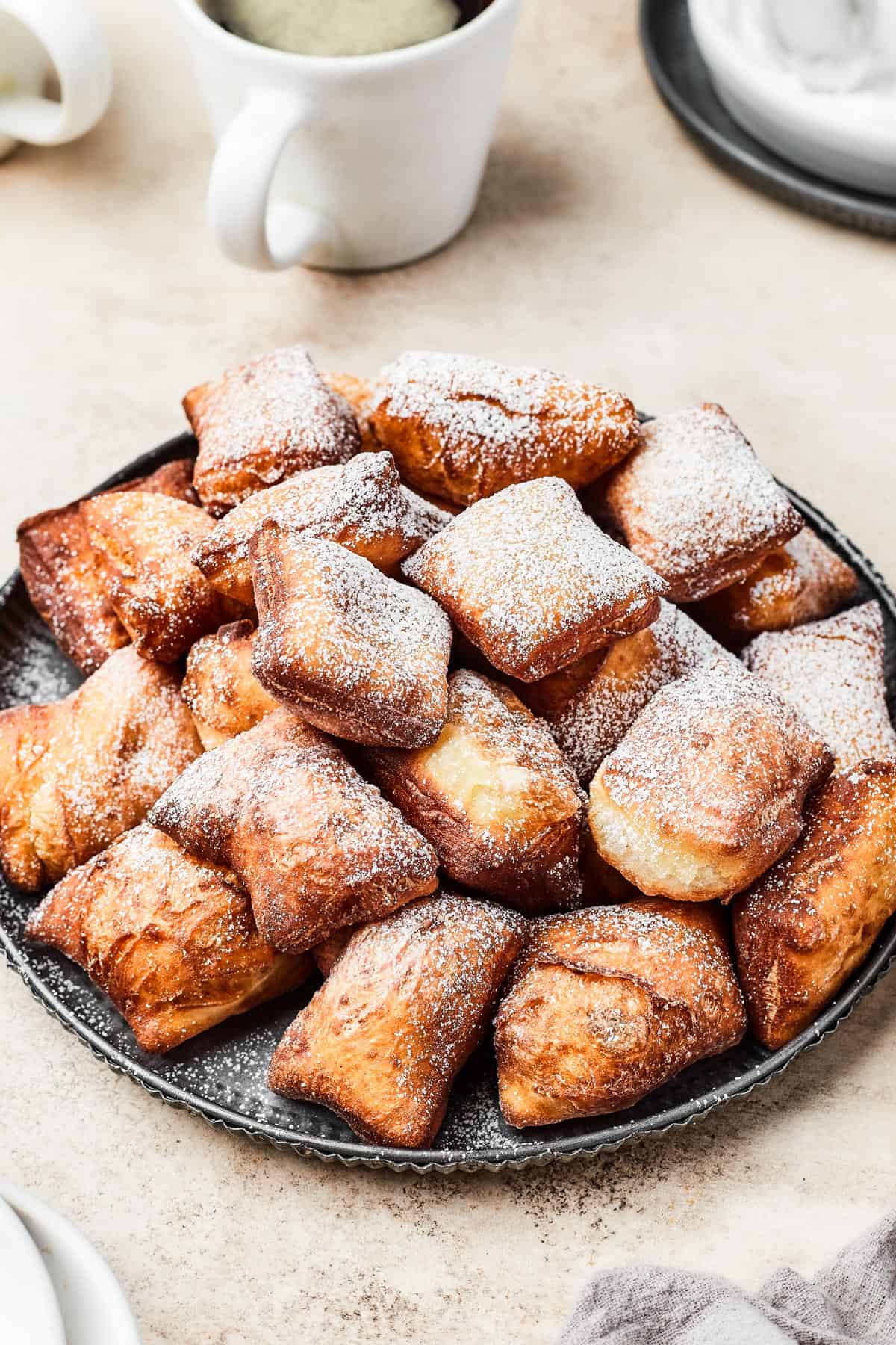 A plate of fried beignets, dusted with powdered sugar.