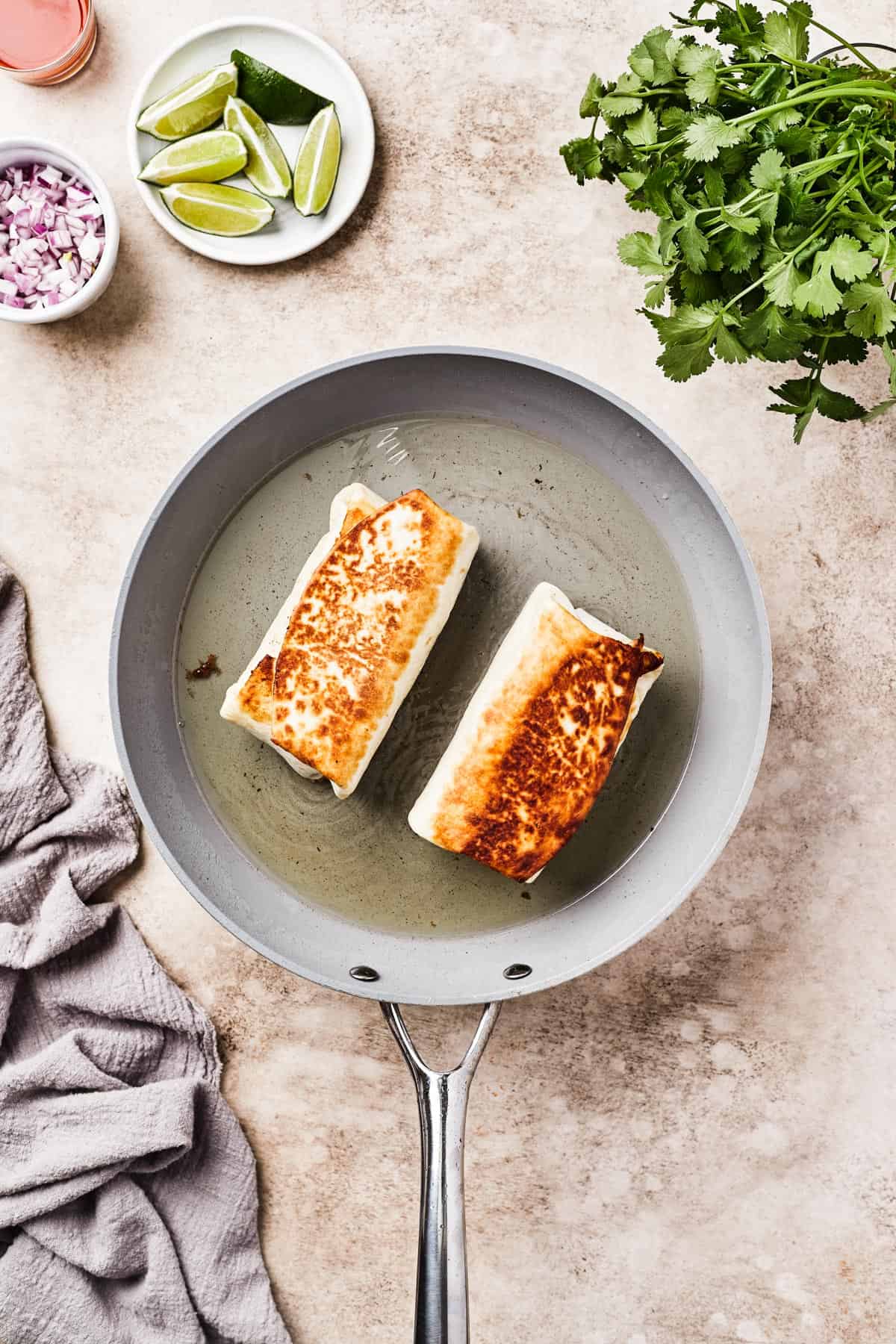 Fried burritos in a skillet with oil.