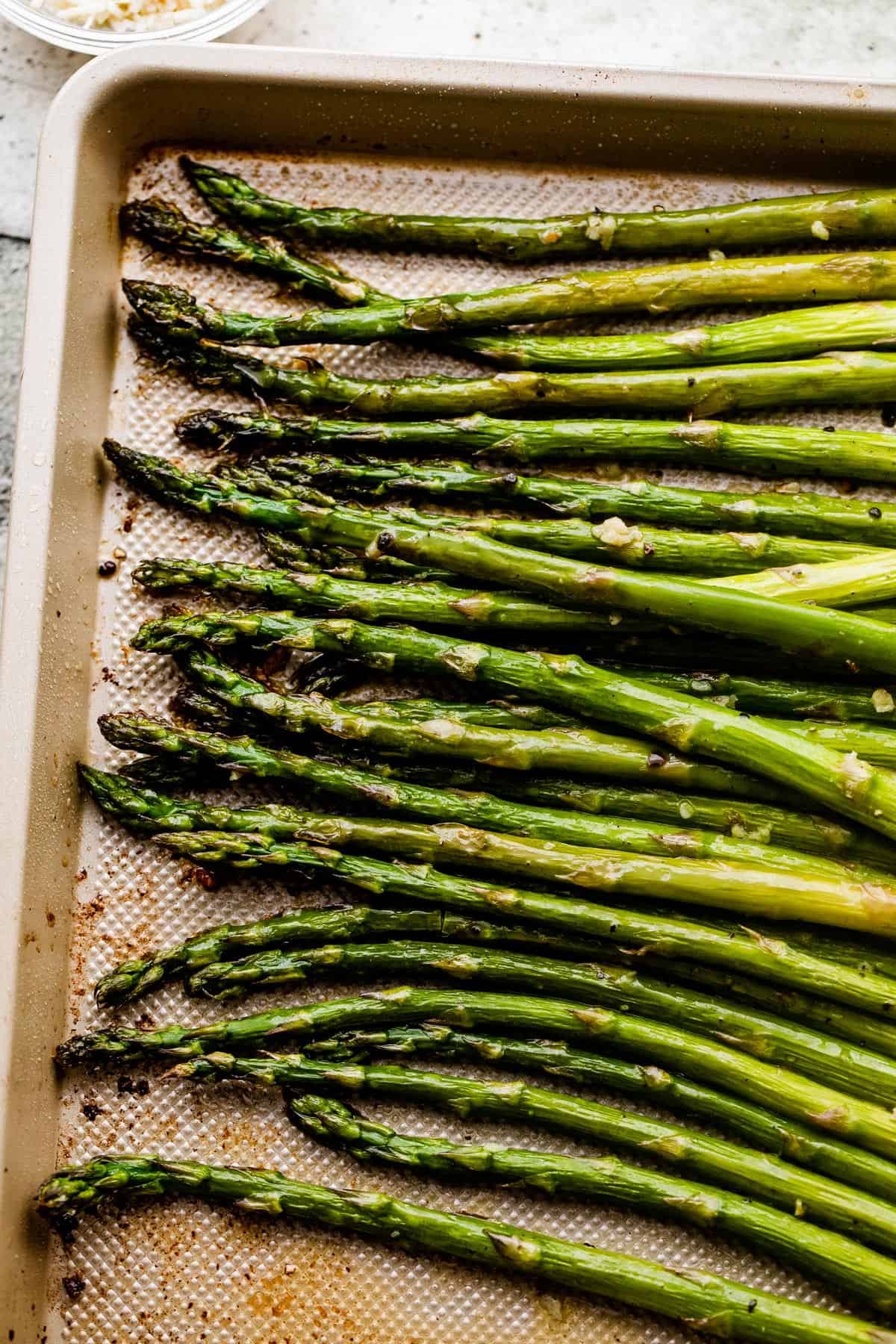 overhead shot of roasted asparagus spears on a baking sheet.