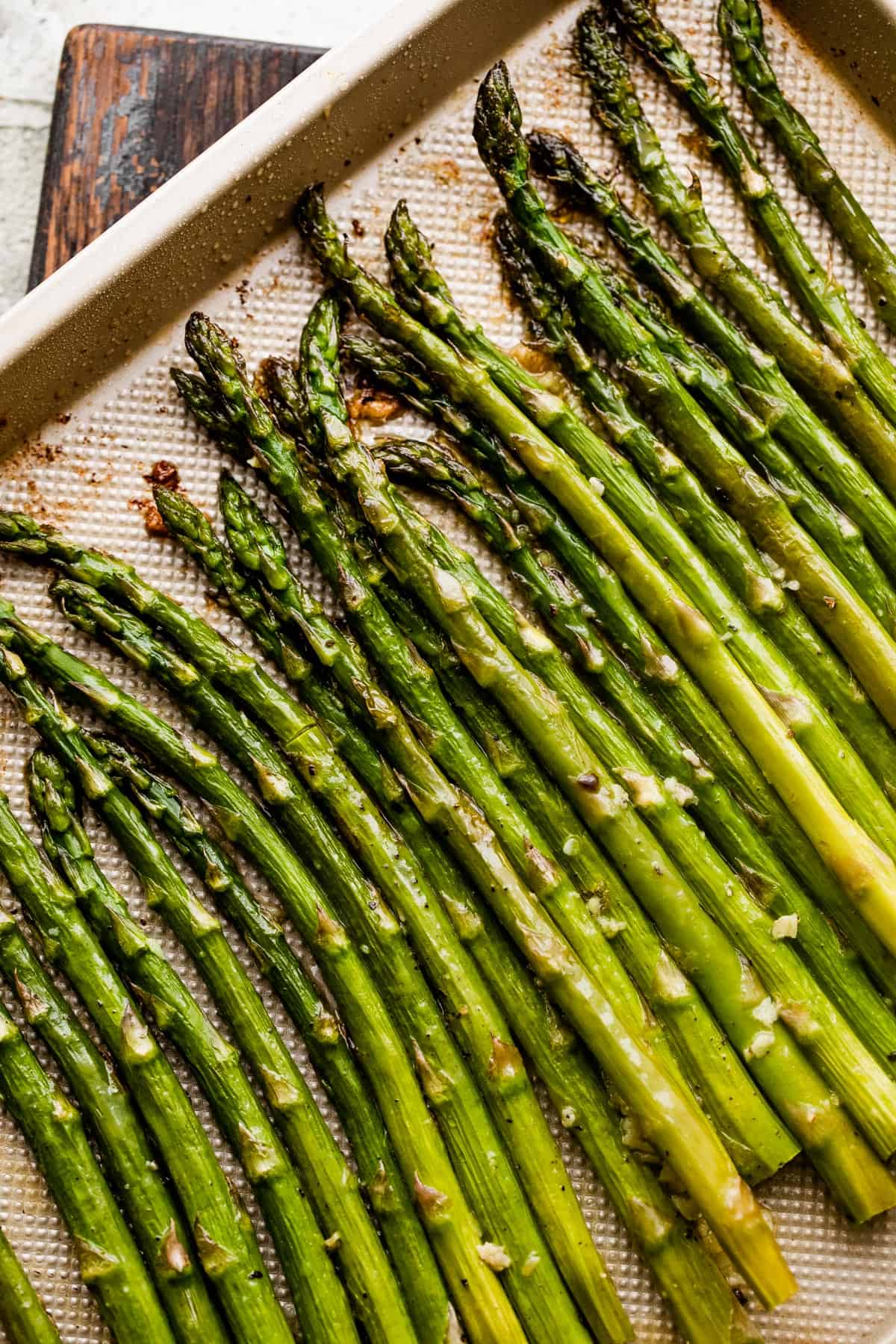 asparagus spears arranged on a gold-colored baking sheet.