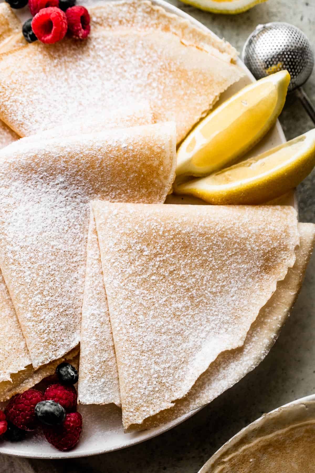 overhead shot of three folded crepes dusted with powdered sugar