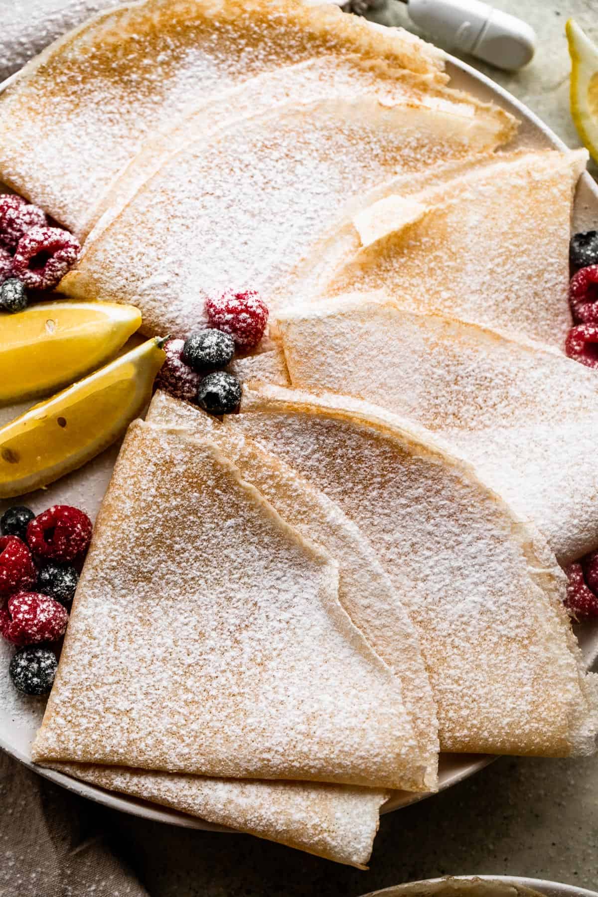 overhead shot of homemade crepes folded over and dusted with powdered sugar.