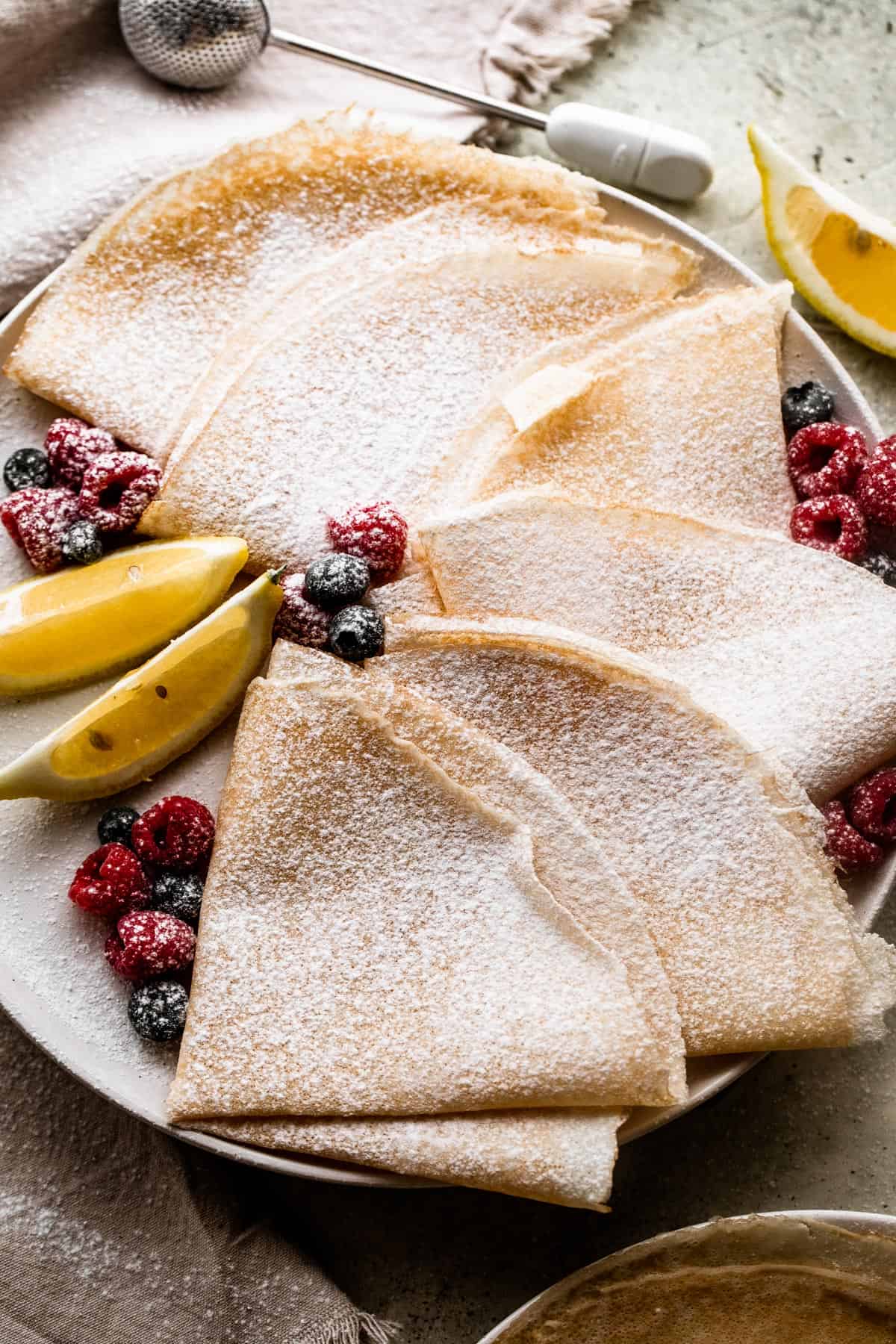 overhead shot of homemade crepes folded over and dusted with powdered sugar.