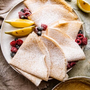 overhead shot of homemade crepes folded over and dusted with powdered sugar.