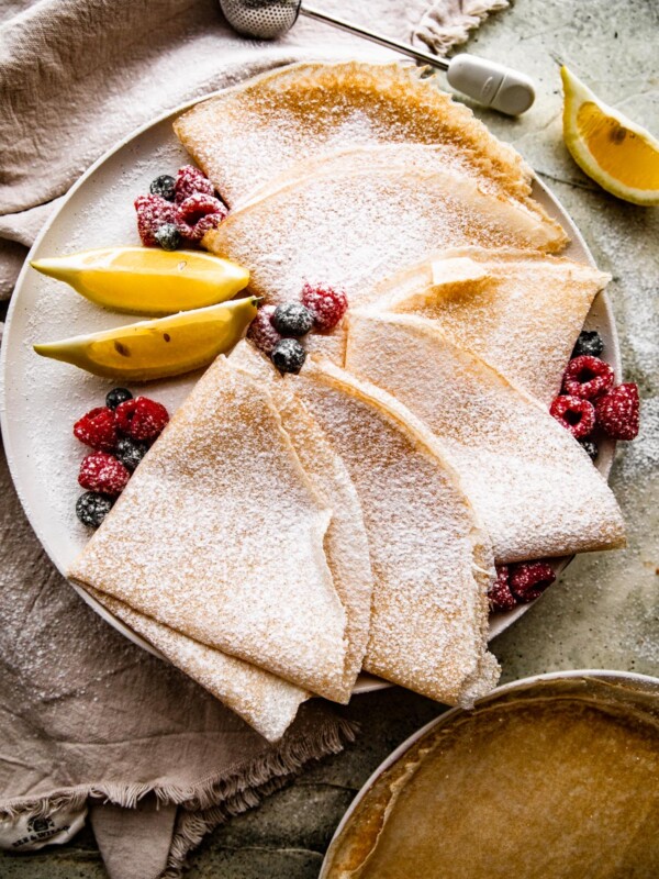 overhead shot of homemade crepes folded over and dusted with powdered sugar.