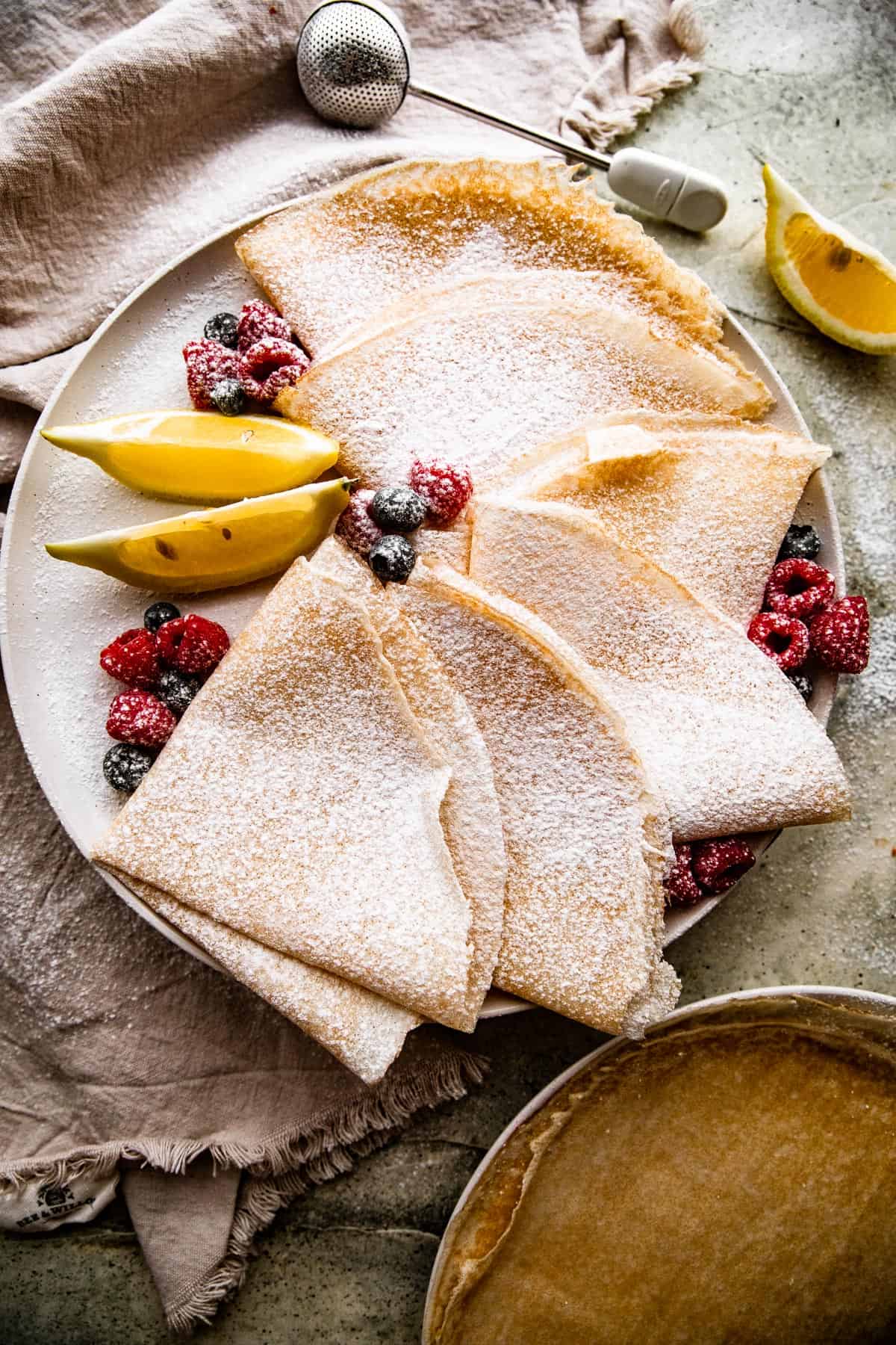 overhead shot of homemade crepes folded over and dusted with powdered sugar.