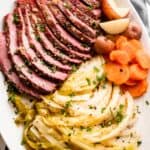 sliced instant pot corned beef, cabbage, carrots, and potatoes arranged on an oval serving platter.