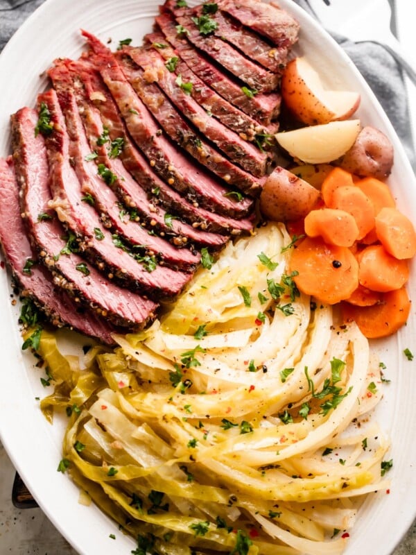 sliced instant pot corned beef, cabbage, carrots, and potatoes arranged on an oval serving platter.