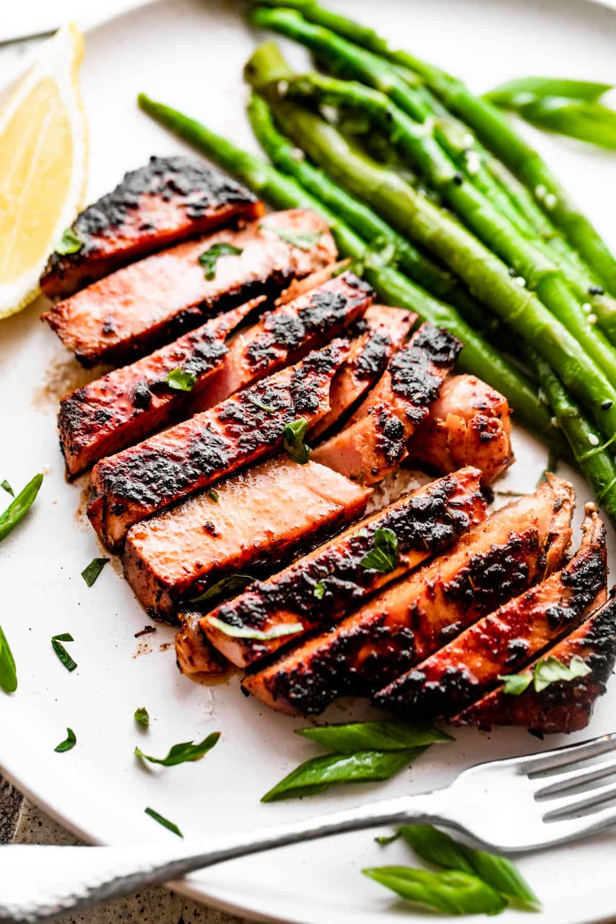 Overhead close-up shot of sliced tuna served on a dinner plate with asparagus stalks.