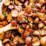 overhead shot of roasted potatoes and bacon in a white skillet.
