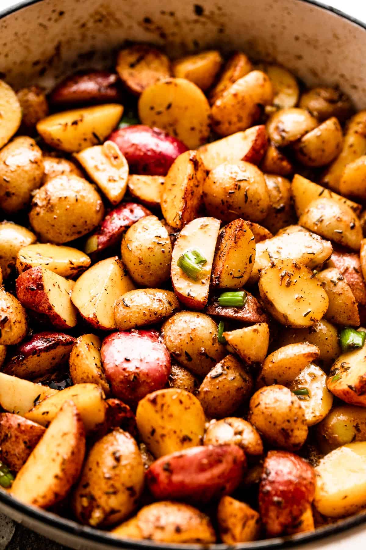 quartered small potatoes in a white skillet.