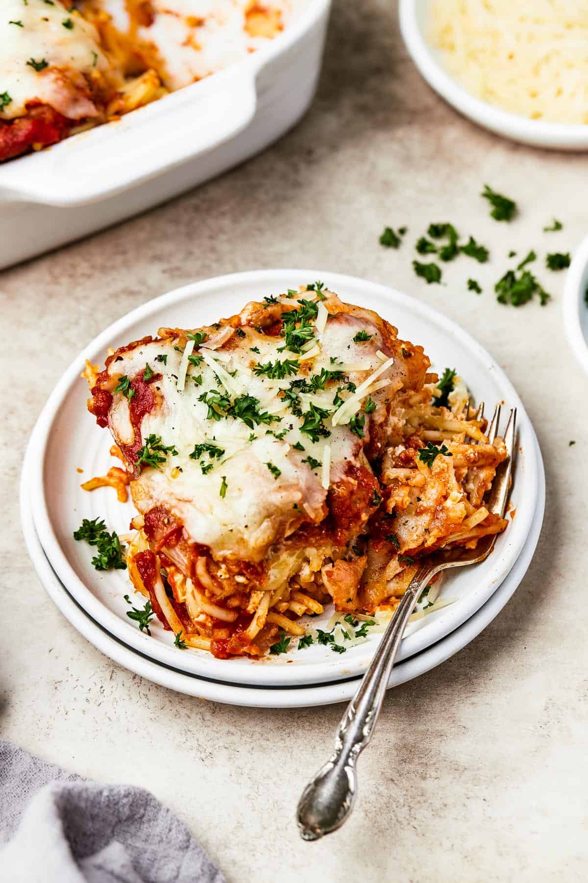 A square of baked spaghetti on a plate, garnished with parsley.