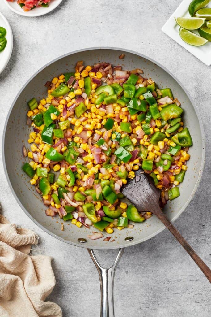 Corn, bell pepper, and onion cooking in a skillet.