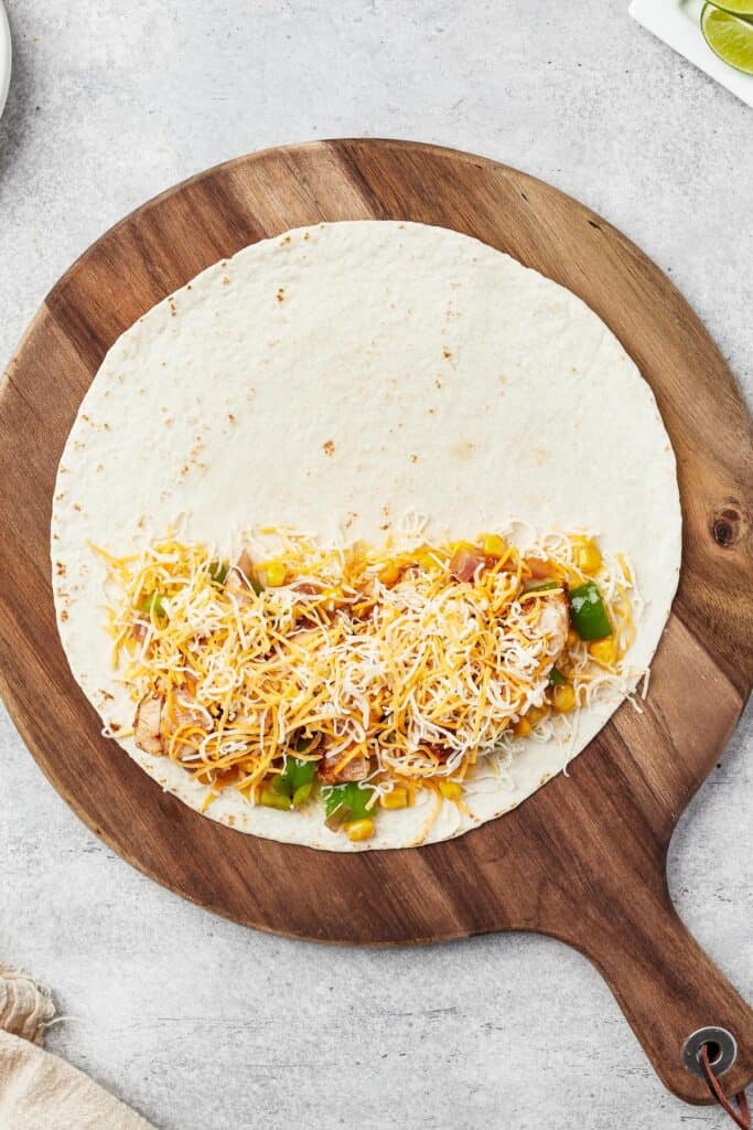 A tortilla with cheese and vegetables on one half.
