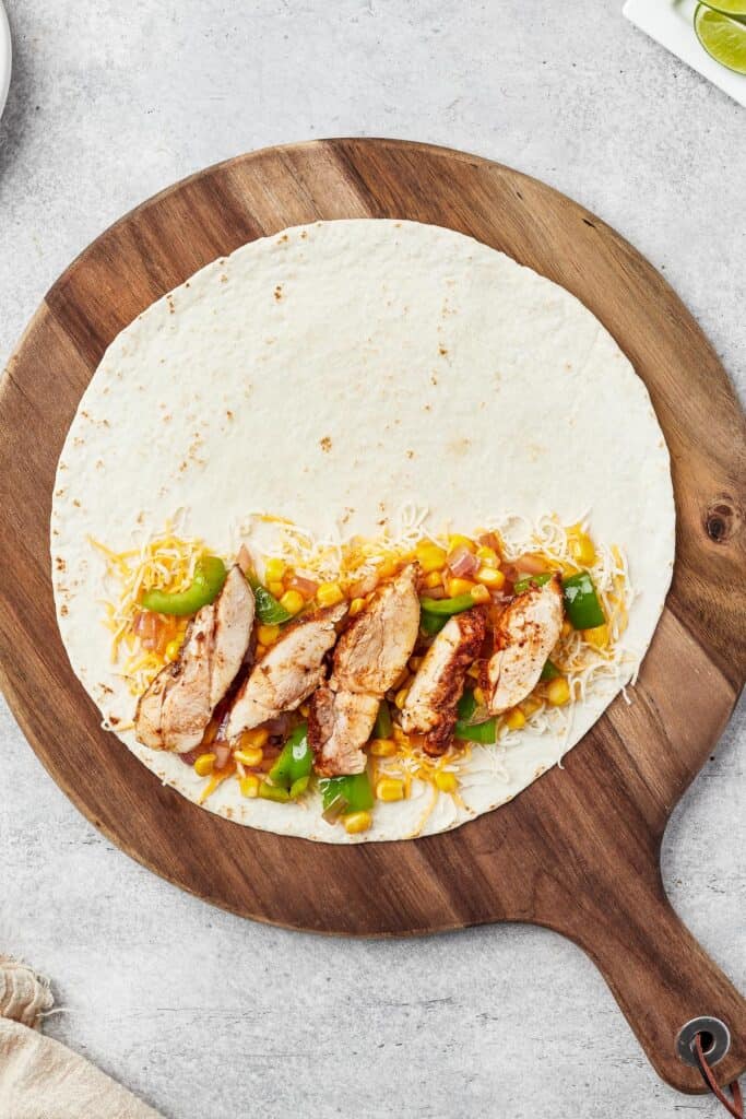 A tortilla with cheese, chicken, and vegetables on one half.