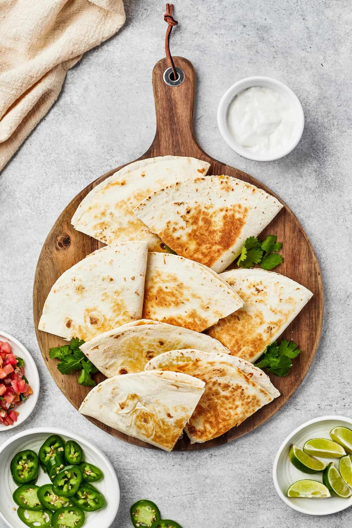 Tortilla wedges fanned out on a wooden board, with jalapeno garnish.