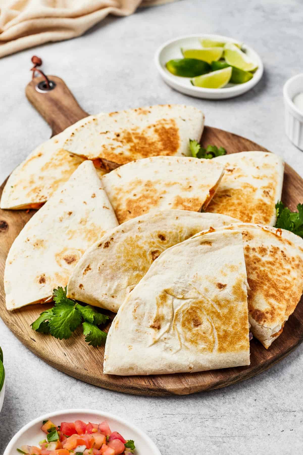 Tortilla wedges fanned out on a wooden board, with jalapeno garnish.