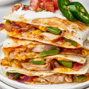 Chicken quesadillas stacked on a plate, viewed from the side to show texture.