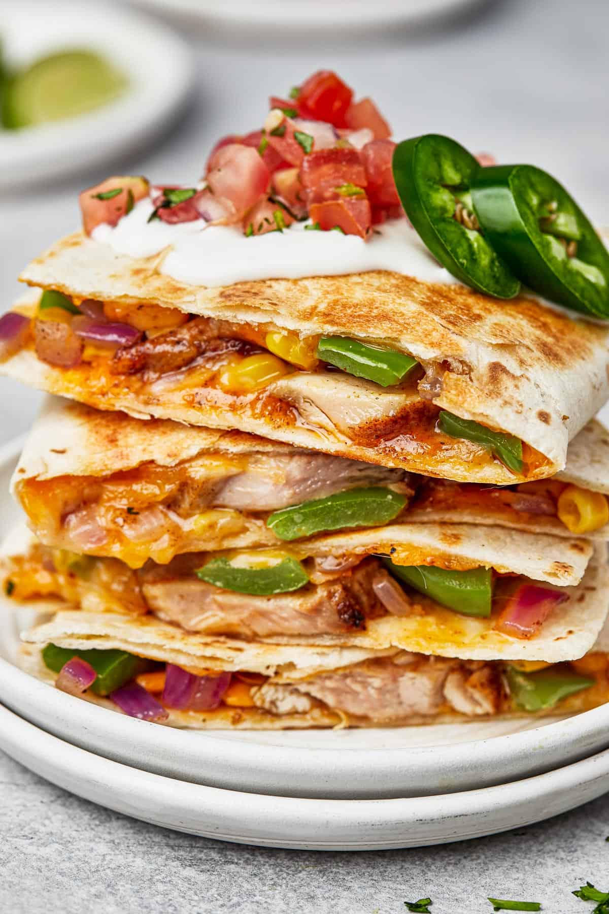 Chicken quesadillas stacked on a plate, viewed from the side to show texture.