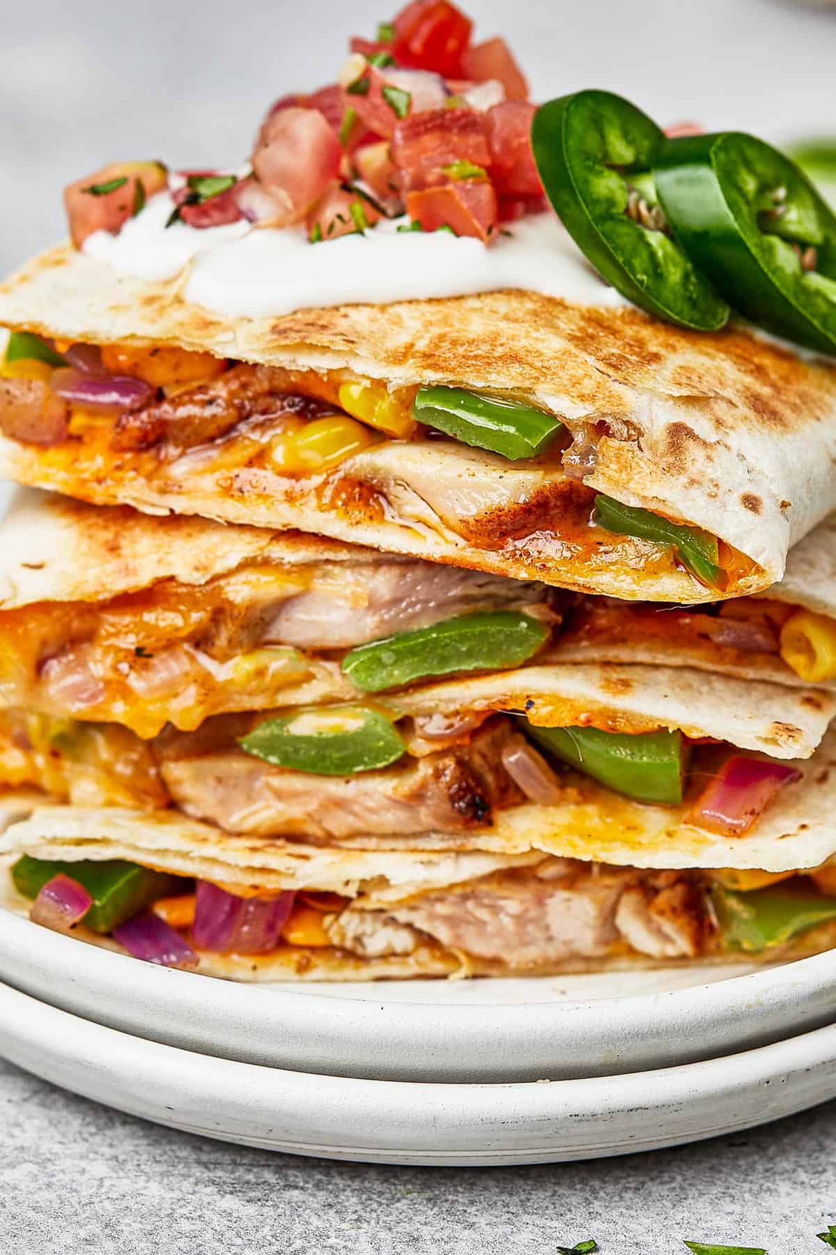 Chicken quesadillas stacked on a plate, viewed from the side to show texture.