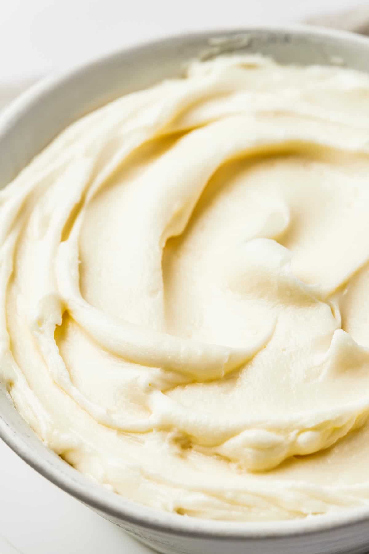 Close-up shot of white frosting, swirled in a large bowl.