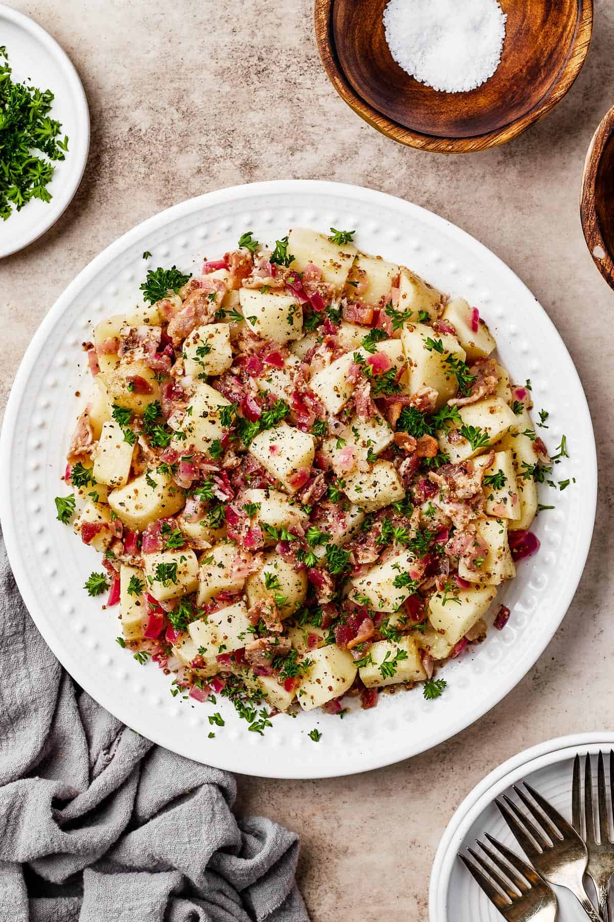 A plate of warm potato salad with herbs and bacon.