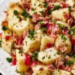 Close-up shot of chopped, boiled potatoes tossed with bacon and dressing.