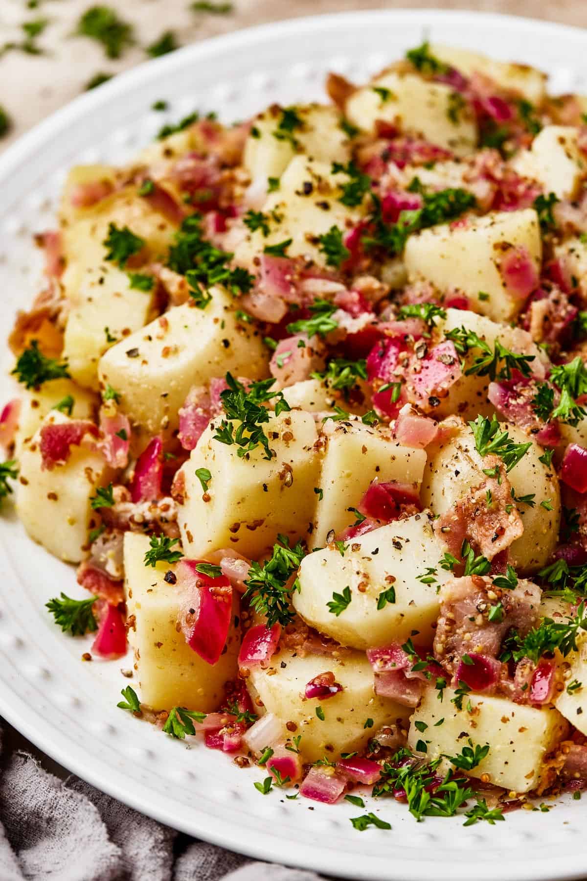 Close-up shot of chopped, boiled potatoes tossed with bacon and dressing.