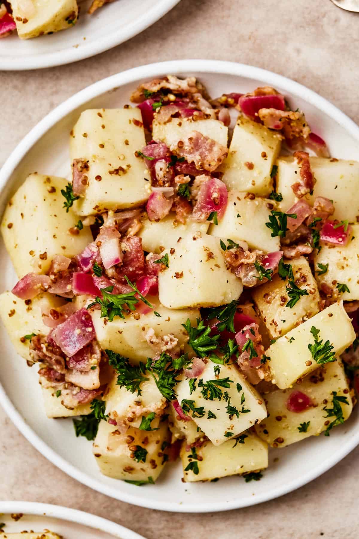 Overhead shot of several small plates, each with a serving of potatoes in bacon dressing.