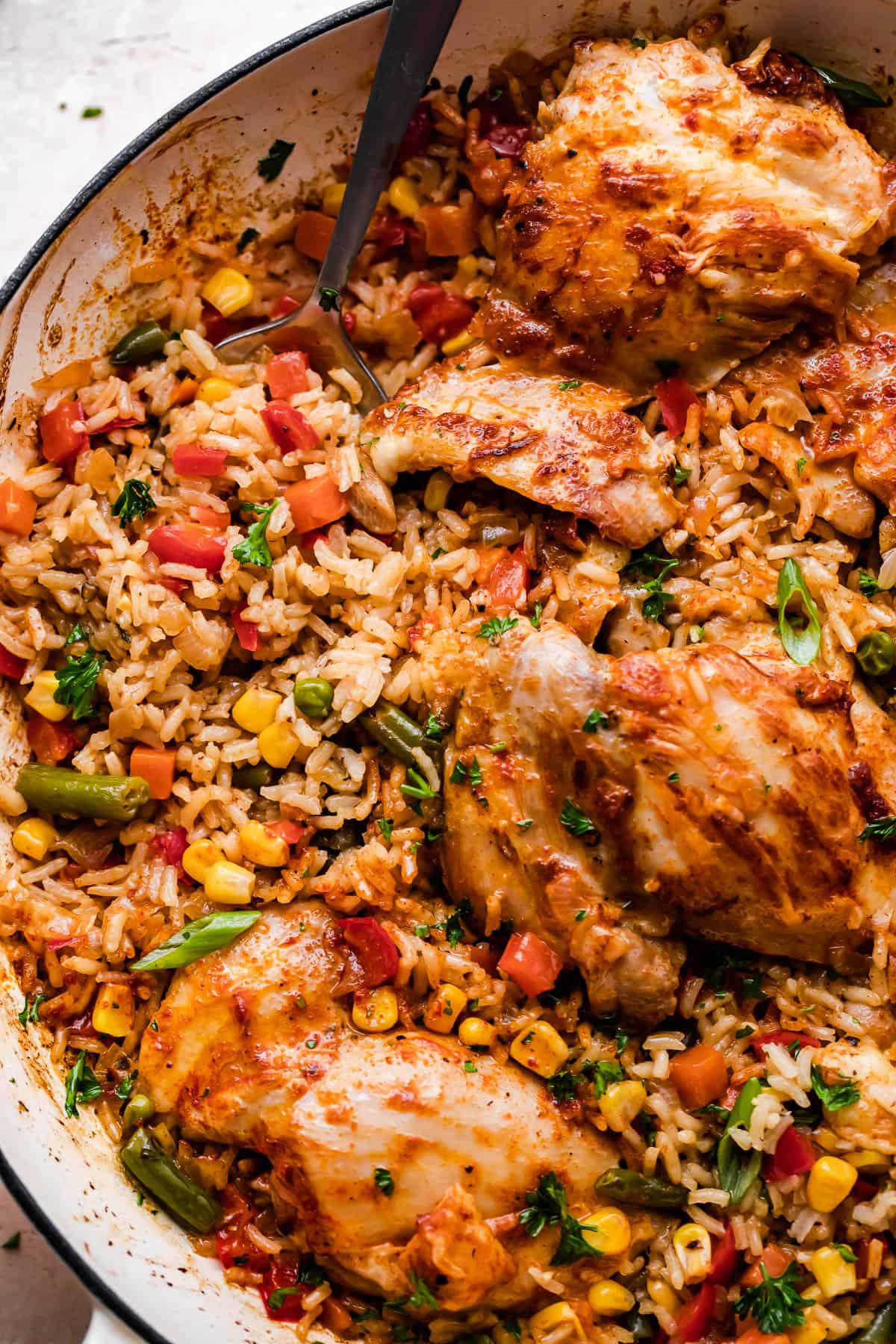 close up overhead shot of a round casserole dish with ranch chicken thighs, rice, and vegetables.