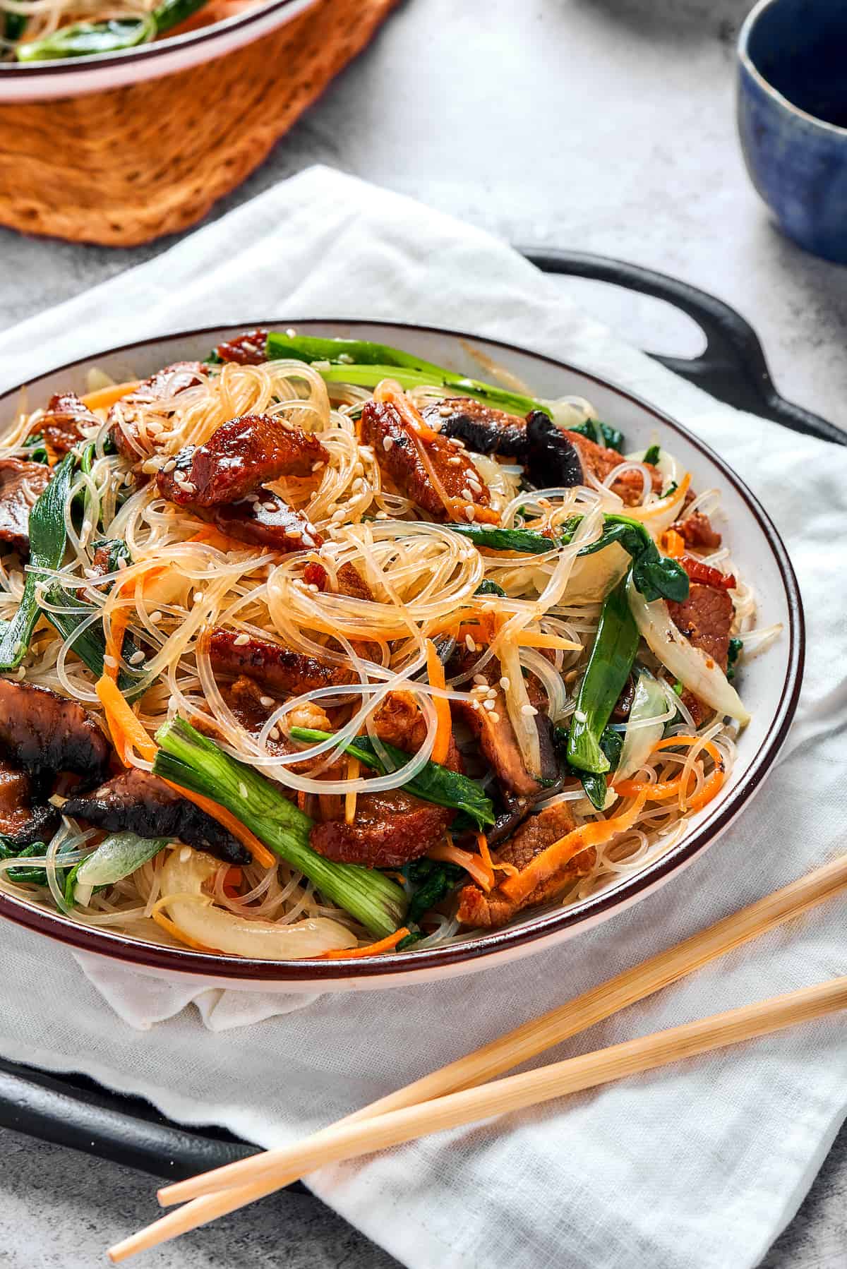 Japchae (Korean glass noodle stir fry) in a serving bowl, with chopsticks.
