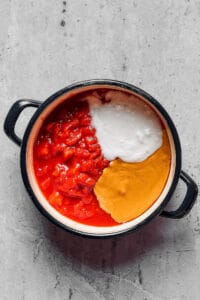 Crushed tomatoes, peanut butter, and coconut milk in a large pot.