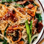 overhead shot of a shallow dish of beef noodle stir fry, garnished with sesame seeds.