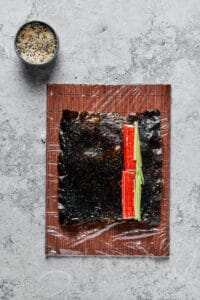 A sheet of nori with surimi (imitation crab) slices and cucumber slices on one side.