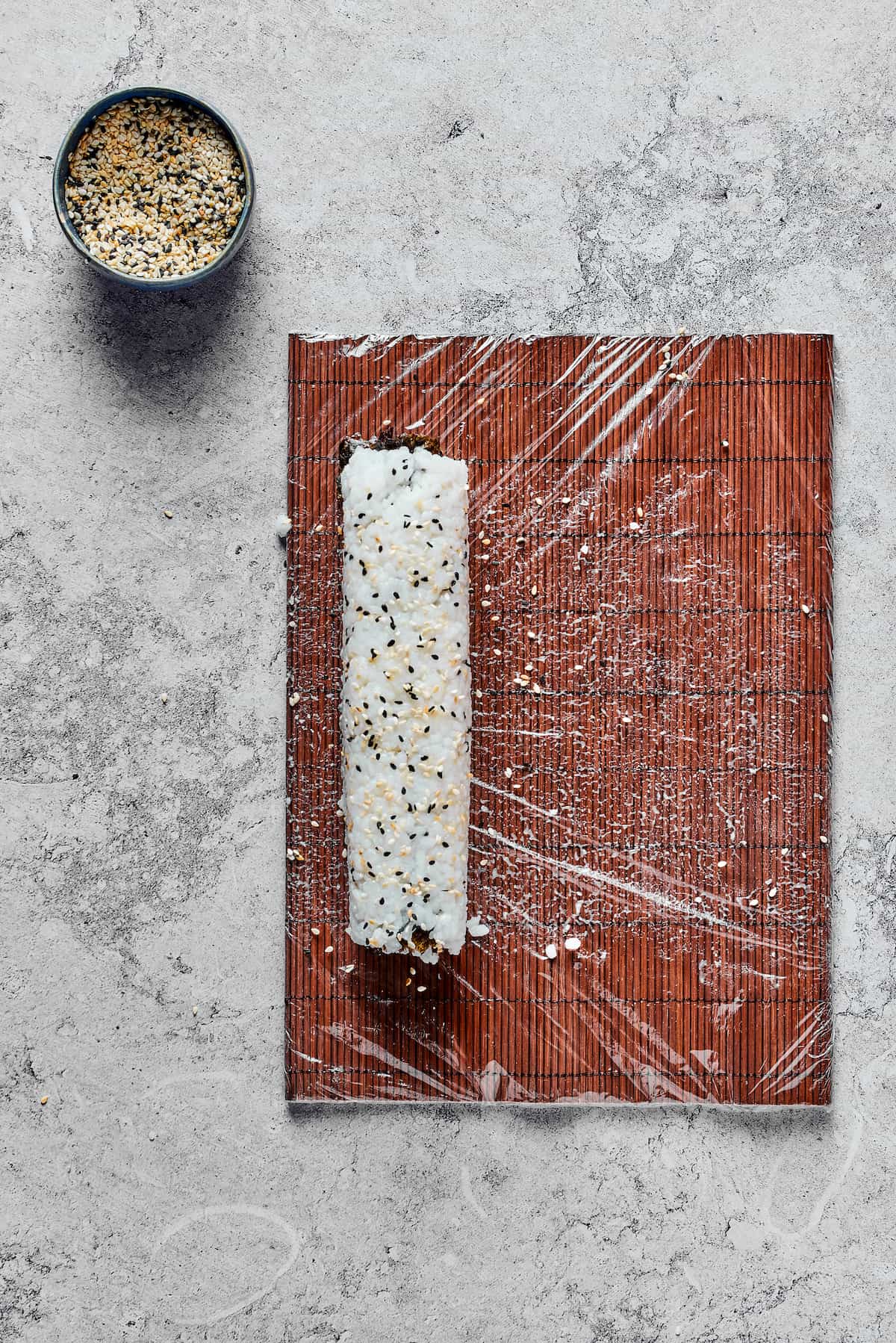 A roll of sushi on a bamboo mat.