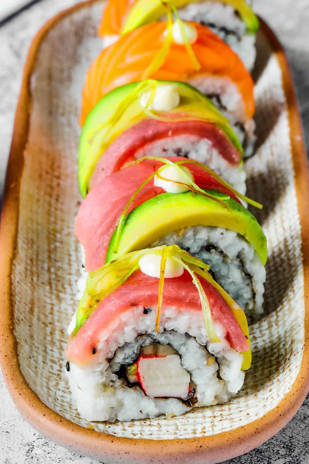 A narrow plate with five pieces of sushi lined up on it.