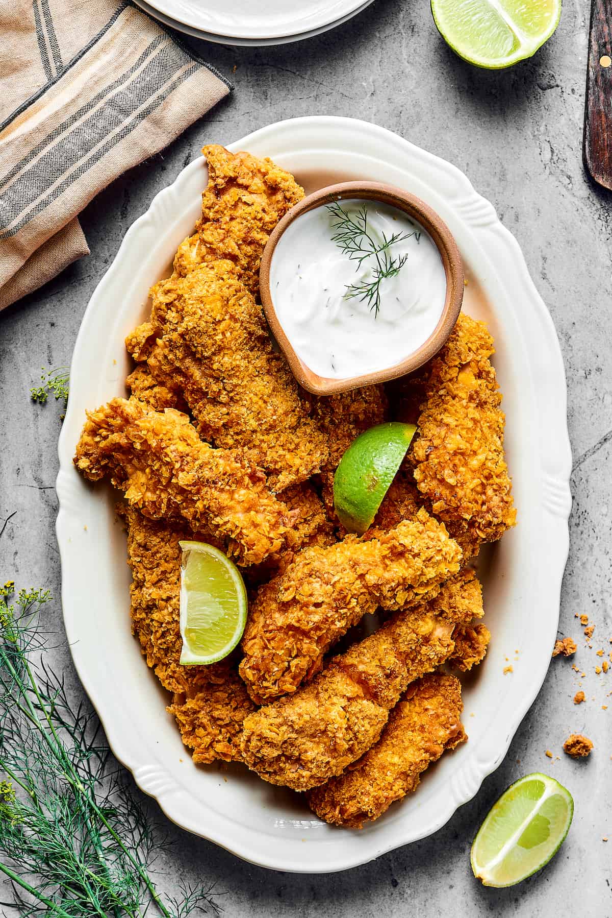Air-fried chicken pieces on a platter garnished with lime wedges and a small dish of dipping sauce.
