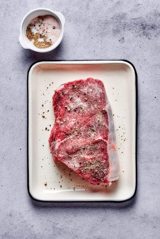 Steak on an enamel pan, sprinkled with salt and pepper.