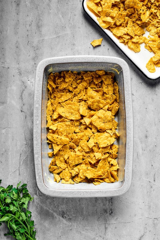 A baking dish with corn chips layered in the bottom.