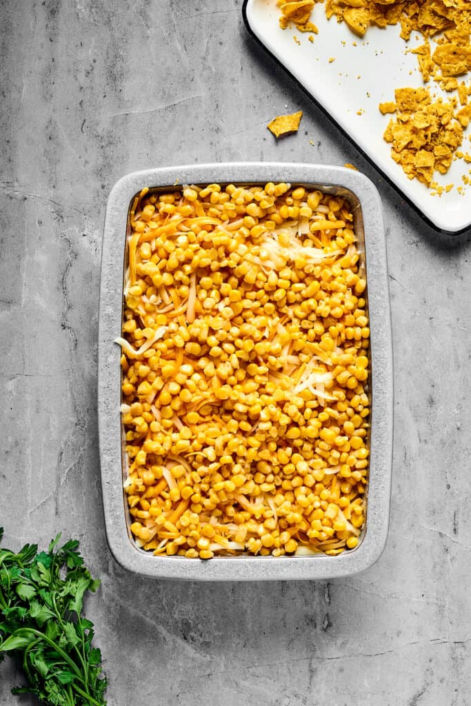 A baking pan with layers of ingredients inside. Corn is the top layer.