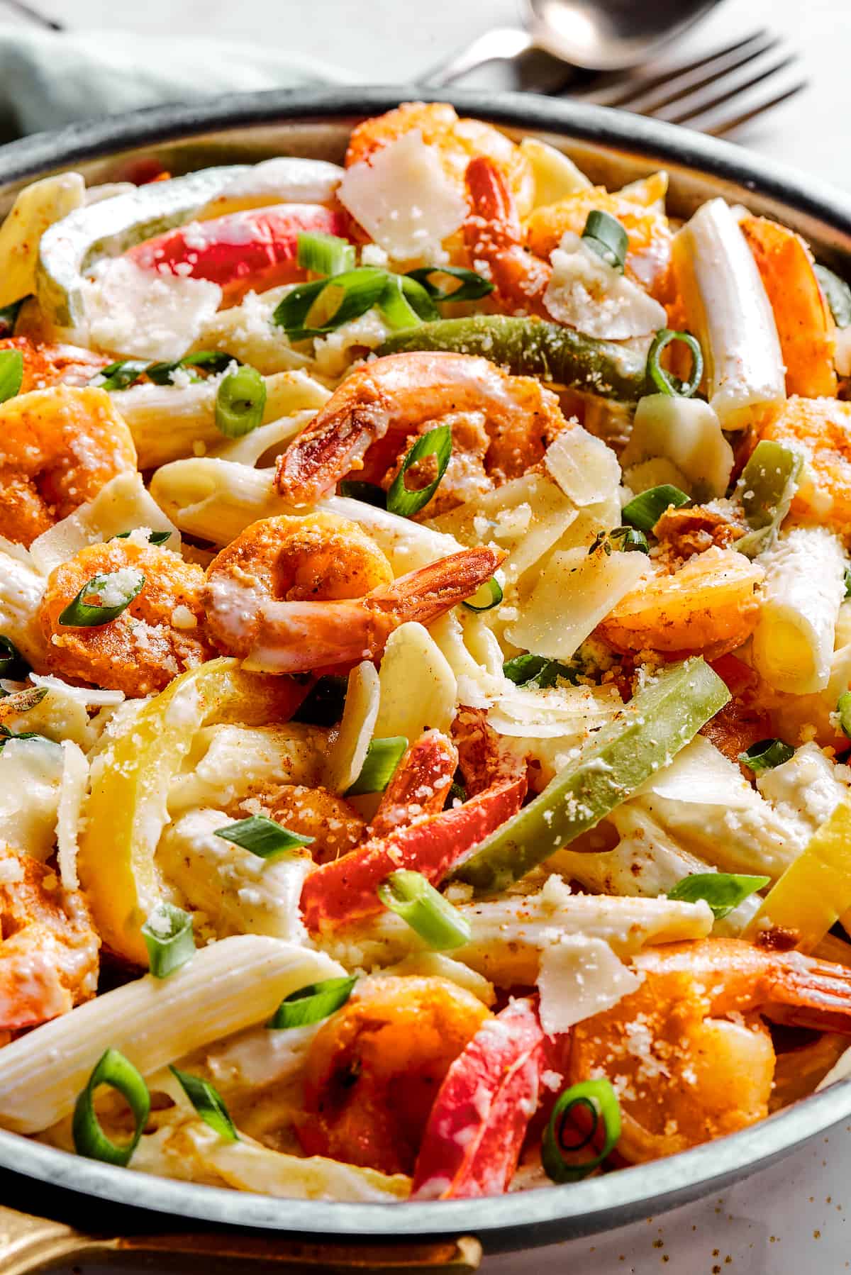 A skillet of bell peppers, pasta, and spicy shrimp in a creamy sauce.