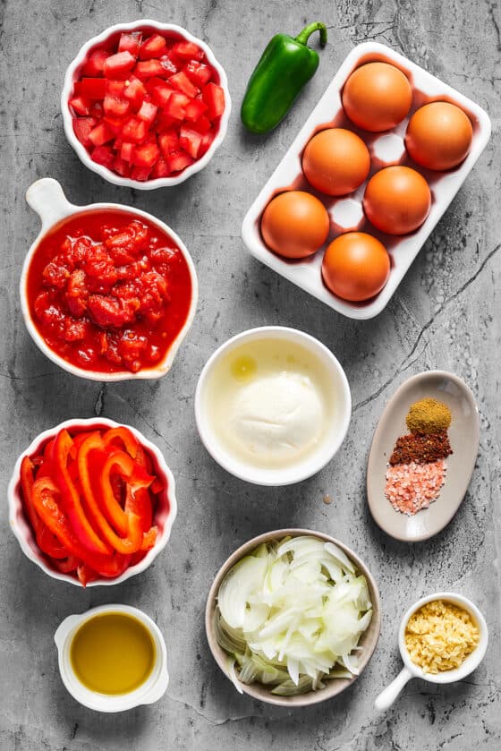 From top left: Chopped fresh tomatoes, a jalapeno pepper, brown eggs, canned crushed tomatoes, fresh mozzarella, seasonings, sliced bell pepper, sliced onion, garlic, olive oil.