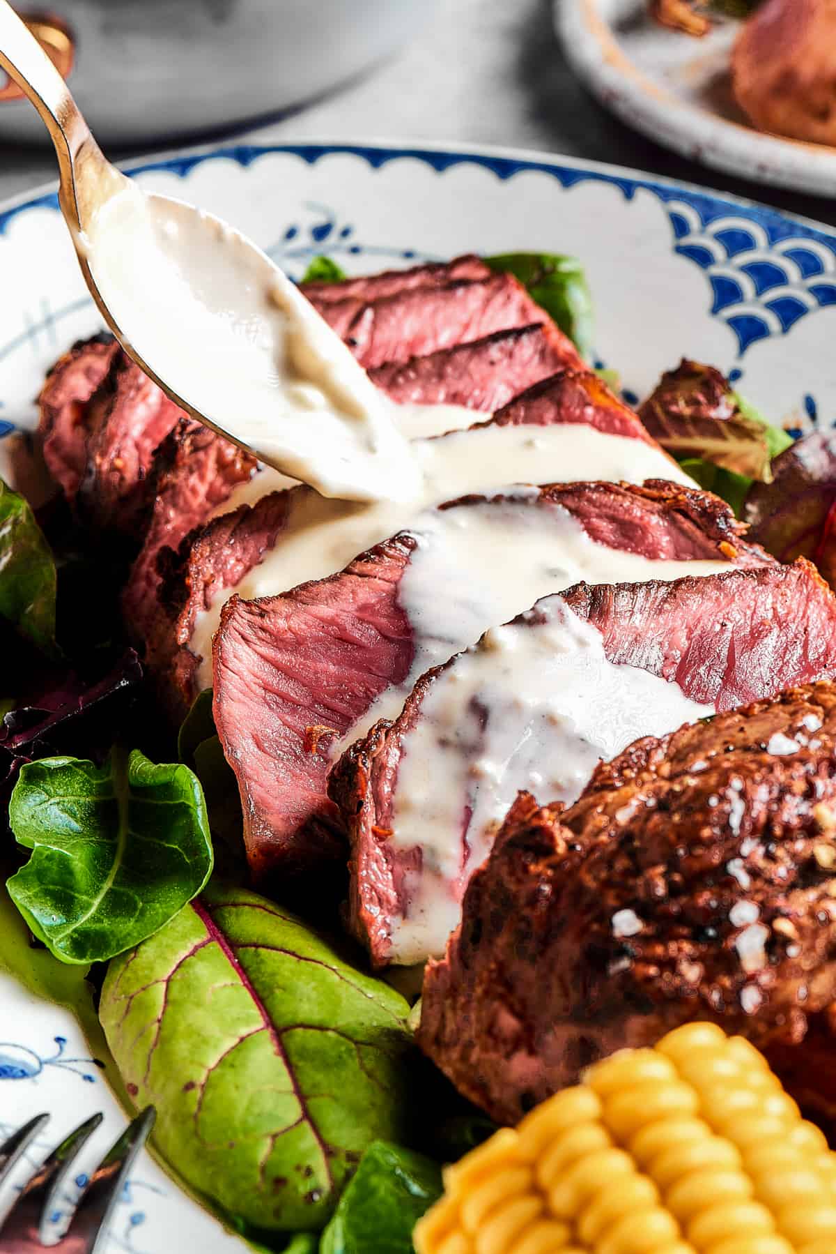 Steak slices with creamy sauce being spooned over the top.