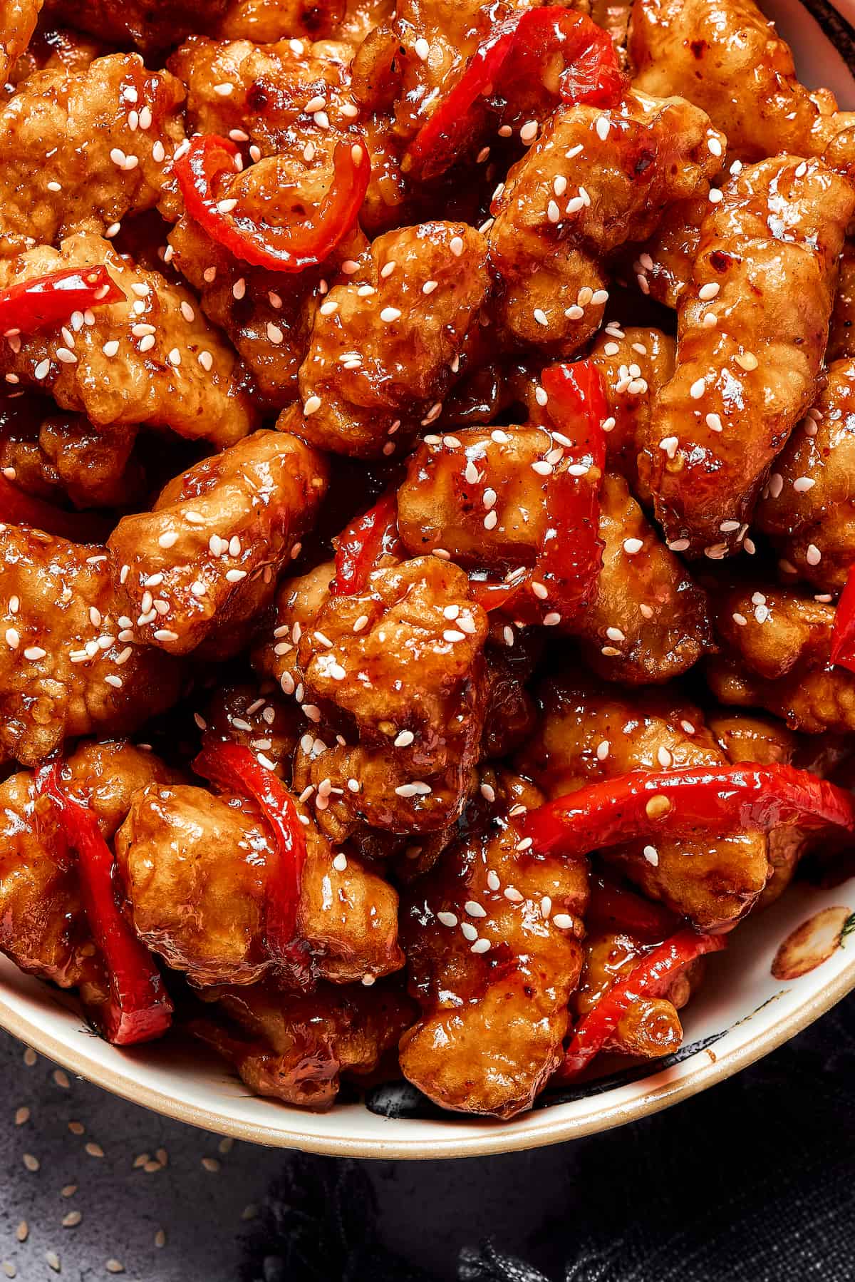 Overhead shot of saucy chicken pieces, garnished with sesame seeds.