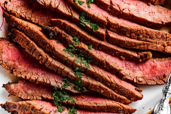 Close up shot of sliced flank steak, showing the texture and medium-rare doneness of the meat.