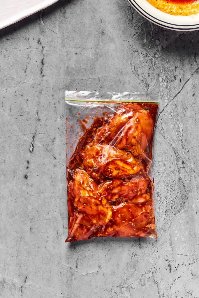 Chicken thighs marinating in a zip-top bag.